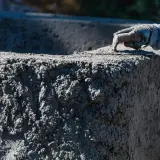 Ręka w rękawicy wygładza świeży beton. Zastanawiasz się, ile kosztuje kubik betonu na budowie?