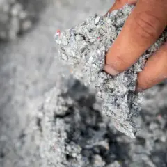 Dłoń trzyma materiał do celuloza ocieplenie. To ekologiczny sposób na izolację domu.