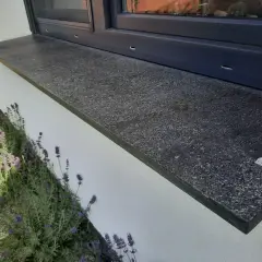 Granitowy parapet zewnętrzny wystaje ok. 5 cm od ściany, chroniąc ją przed deszczem. Obok kwitnie lawenda.