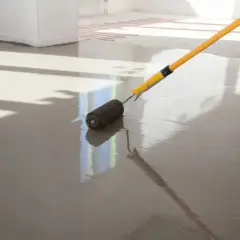 Wałek do betonu z kolcami rozprowadza świeży wylewany **anhydryt** na podłodze z ogrzewaniem podłogowym.