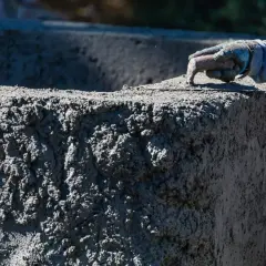 Ręka w rękawicy wygładza świeży beton. Zastanawiasz się, ile kosztuje kubik betonu na budowie?