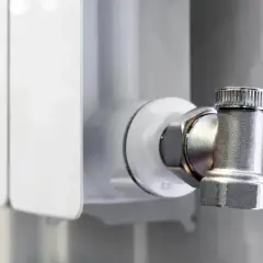 Metalowy zawór przy grzejniku, gotowy do podłączenia grzejnika od dołu.
