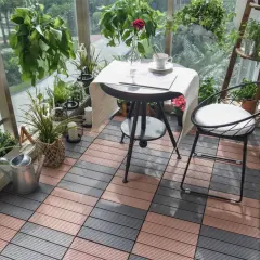 Czym wyłożyć balkon? Drewnopodobne płytki tarasowe w kolorze brązowym i szarym tworzą przytulną przestrzeń z roślinami i meblami.