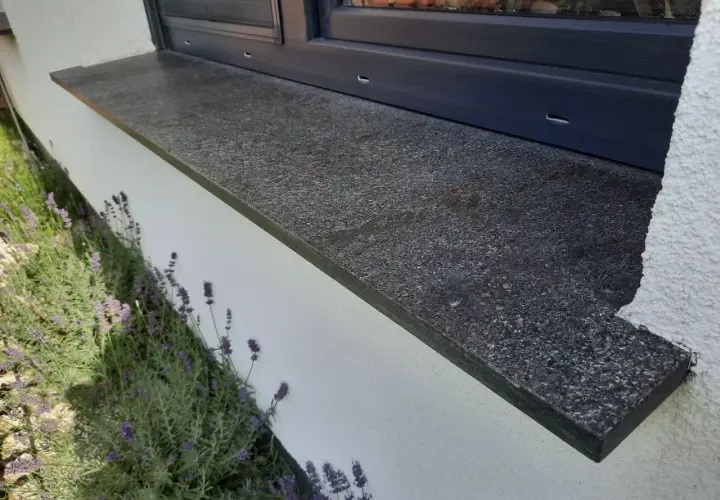 Granitowy parapet zewnętrzny wystaje ok. 5 cm od ściany, chroniąc ją przed deszczem. Obok kwitnie lawenda.