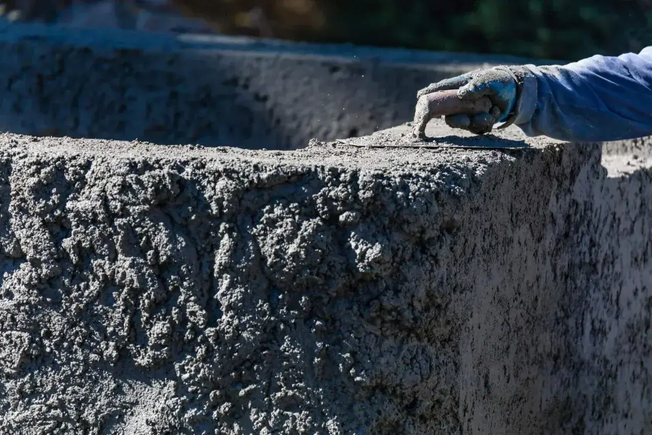 Ręka w rękawicy wygładza świeży beton. Zastanawiasz się, ile kosztuje kubik betonu na budowie?