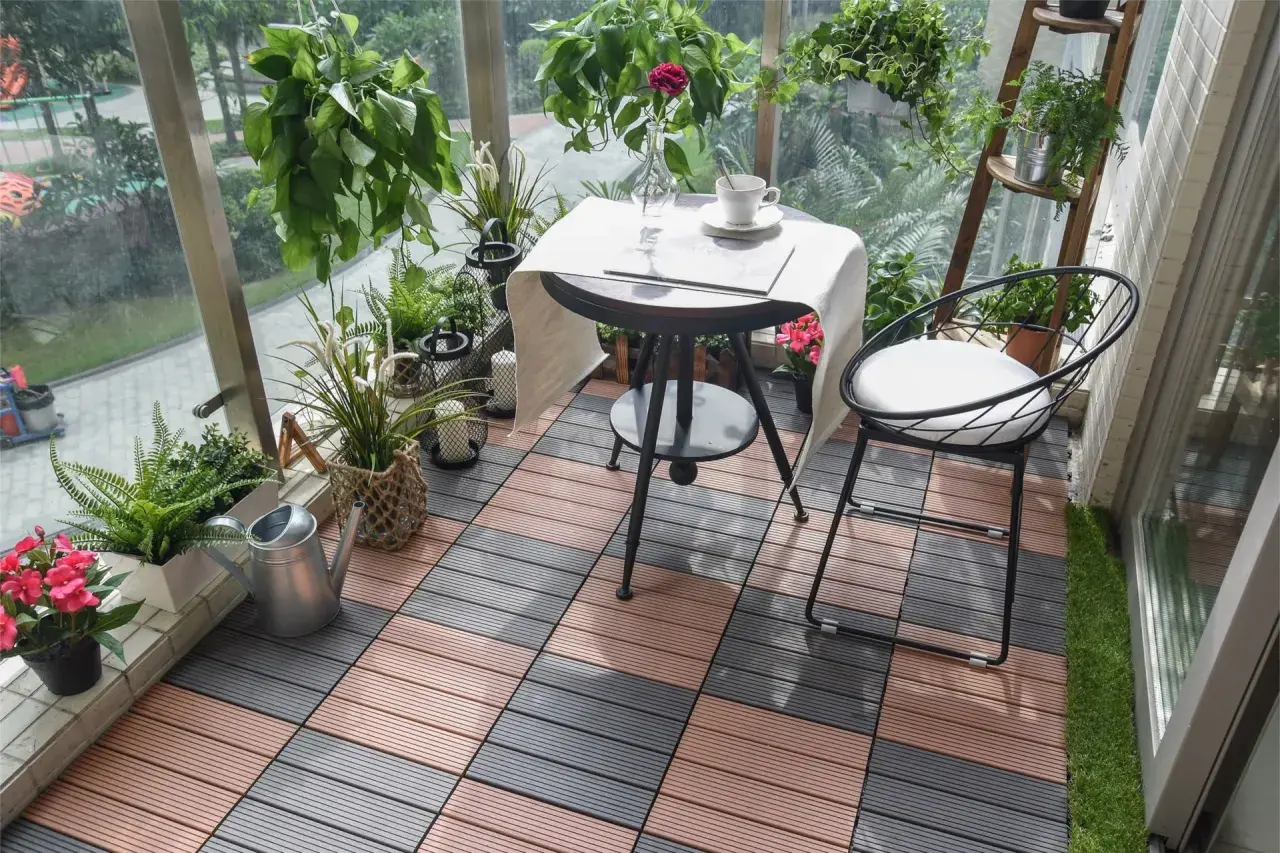 Czym wyłożyć balkon? Drewnopodobne płytki tarasowe w kolorze brązowym i szarym tworzą przytulną przestrzeń z roślinami i meblami.