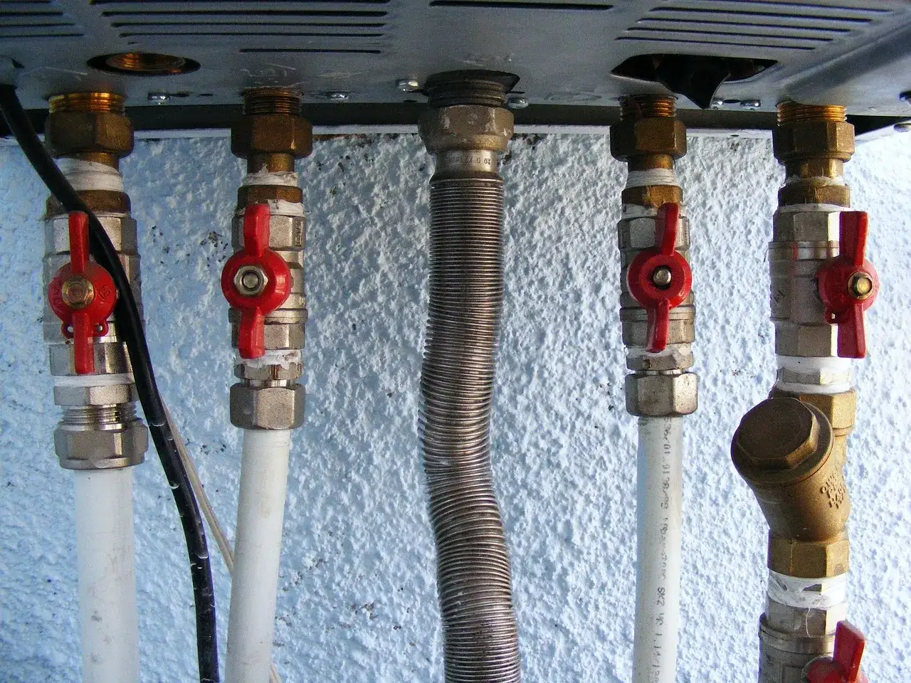 Instalacja hydrauliczna z zaworami i rurami. Widoczna jest metalowa otulina elastycznego przewodu.